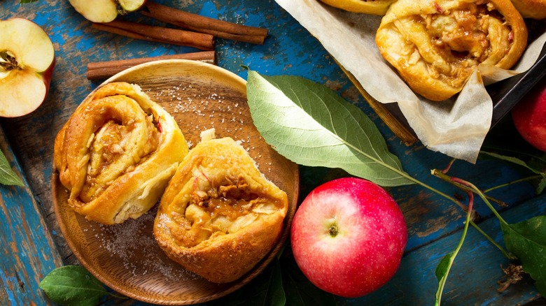Top-down view of plated cinnamon rolls with apples and cinnamon sticks