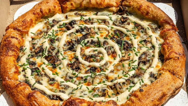 A Holy Shiitake mushroom pizza from Mellow Mushroom in a pizza box with the sun shining on it.