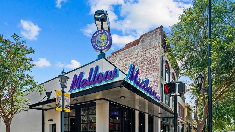 The vibrant, funky exterior of a Mellow Mushroom location with a toy car placed on top of the sign.