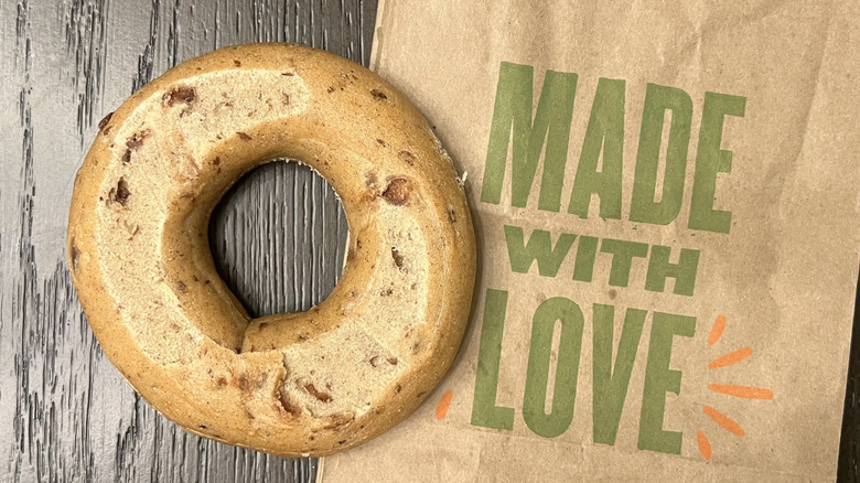 Panera cinnamon raisin bagel and paper bag on wood surface