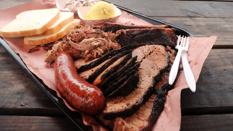 a Texas barbecue platter with brisket, smoked sausage, pulled pork, potato salad, coleslaw, and white bread