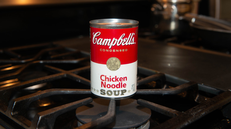 Campbell's Chicken Noodle Soup in a can displayed on a home stovetop