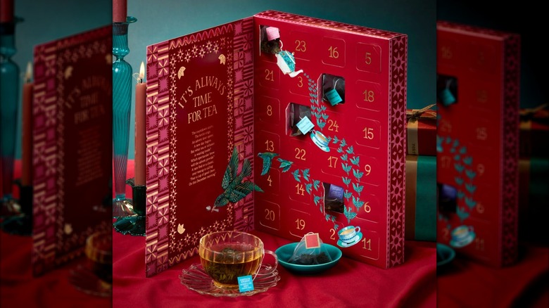 the open advent calendar in deep red with a glass mug of brewed tea in front