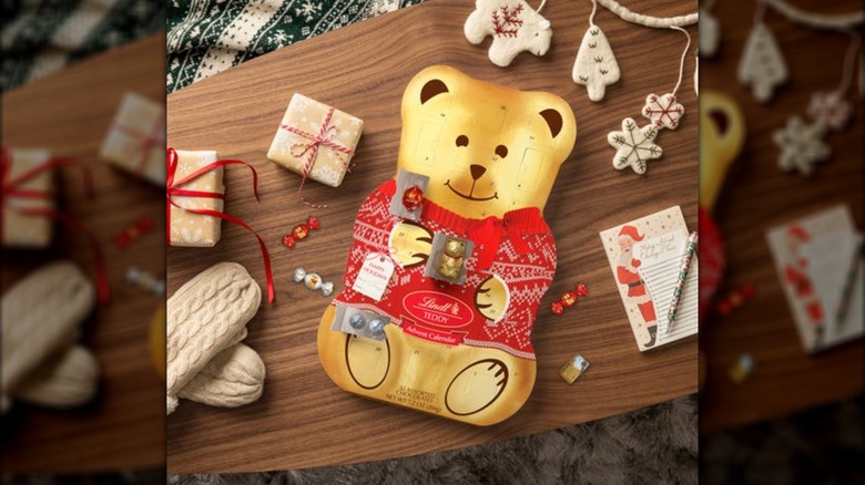 the teddy bear calendar with a few slots opened on a wooden table surrounded by holiday items