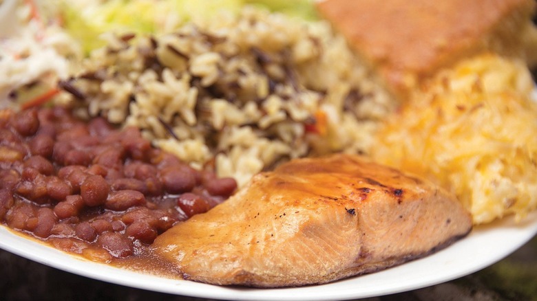 Grilled salmon on plate with beans, rice, and sides