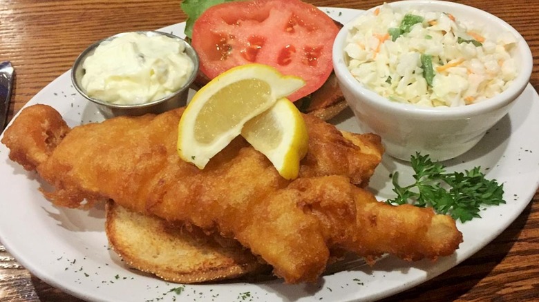 Fish fry with lemon slices, tomato, tartar sauce, and coleslaw