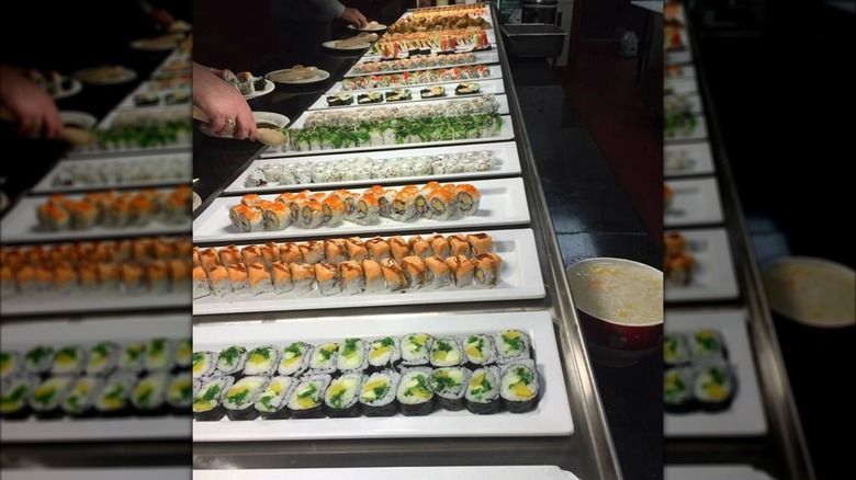 Buffet lined with trays of assorted sushi