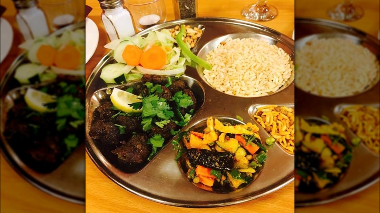 Silver tray with assortment of mets, rices, and veggie dishes