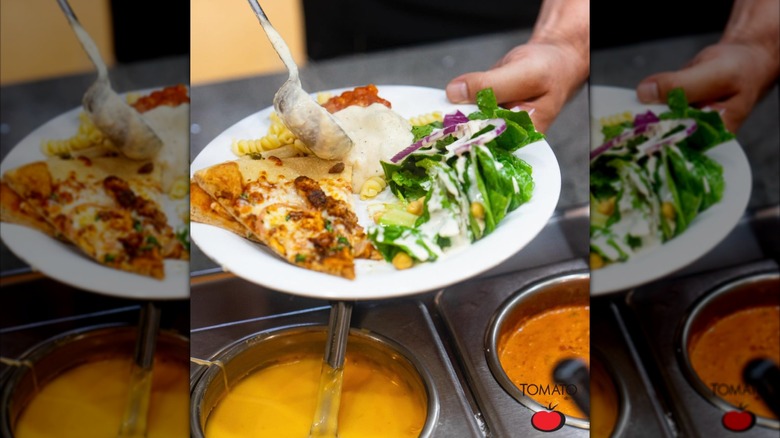 Putting sauce on plate with pizza, pasta, and salad at a buffet