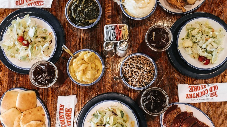 Assorted dishes with salad, greens, peas, biscuits, and drinks on wooden table