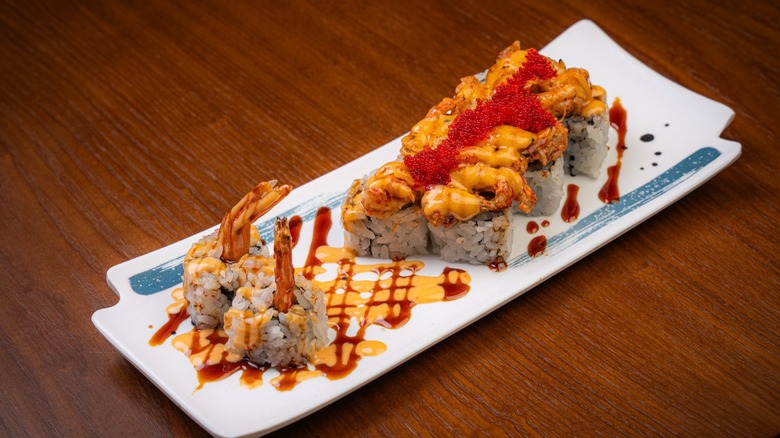 White plate with sushi rolls on wooden table