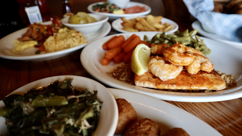 Plates of Cracker Barrel food including shrimp and salmon on table