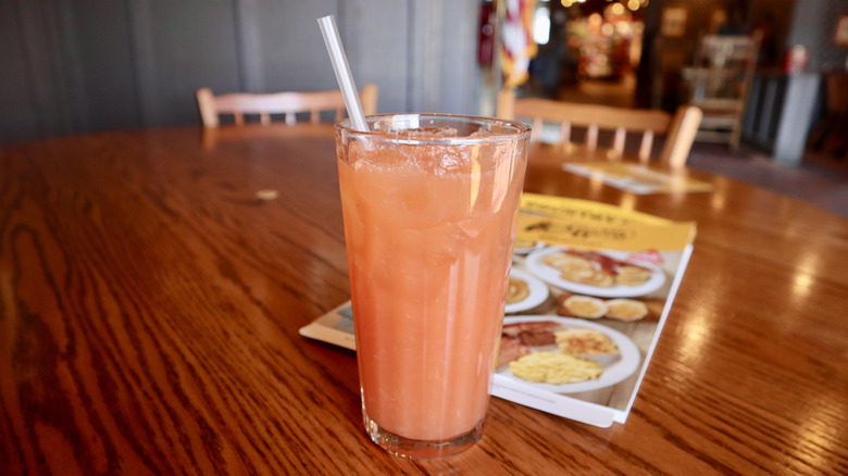 glass of pink strawberry lemonade with Cracker Barrel menu in background