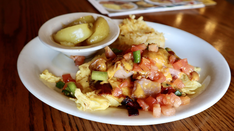 Cracker Barrel Farmhouse Scramble topped with meat, cheese, vegetables with apples on plate