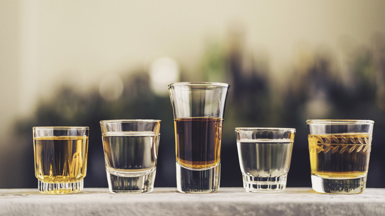A row of shot glasses filled with different types of liquor