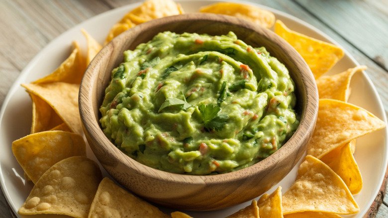 A bowl of guacamole surrounded by chips