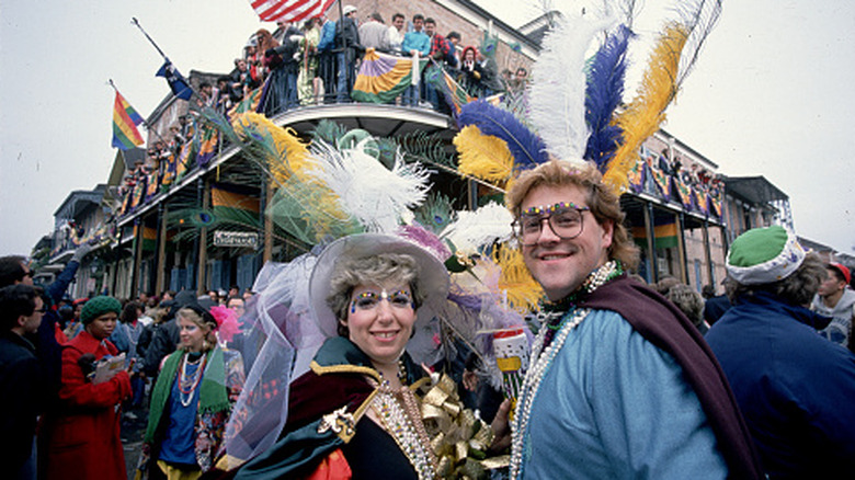 A couple poses in costume at a Mardi Gras parade in the French Quarter.