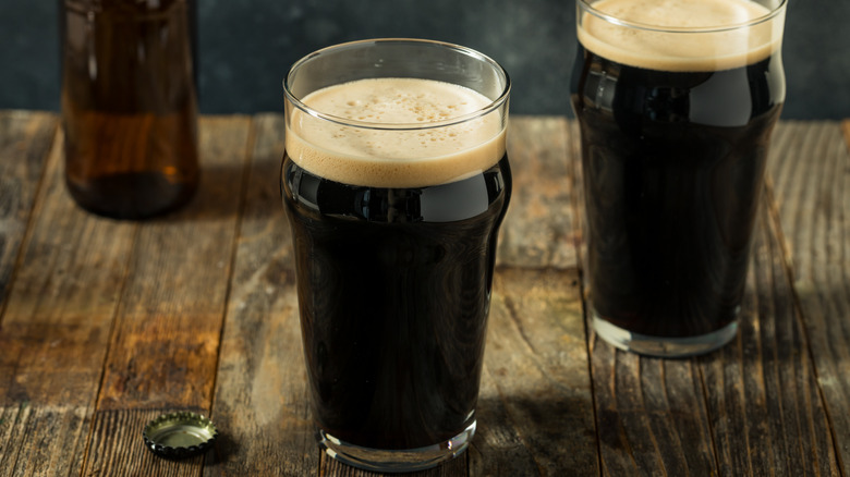 Two glasses of porter beer on a wood table.