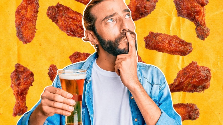 Man holding beer with wings in background