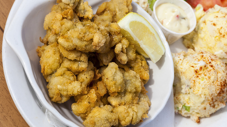 Fried clams with a side of potato salad on a plate