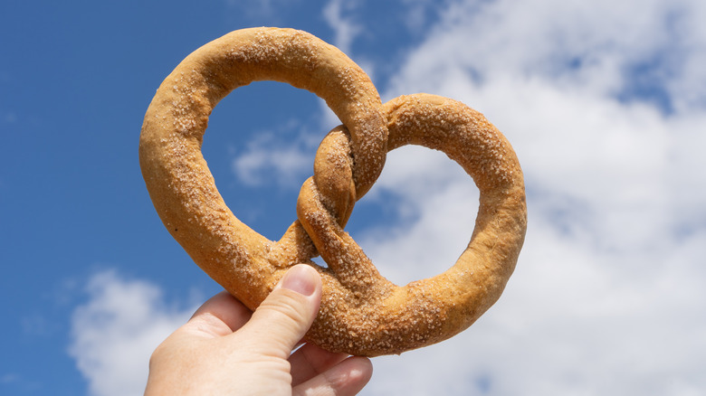 Someone holding a soft pretzel up to the sky
