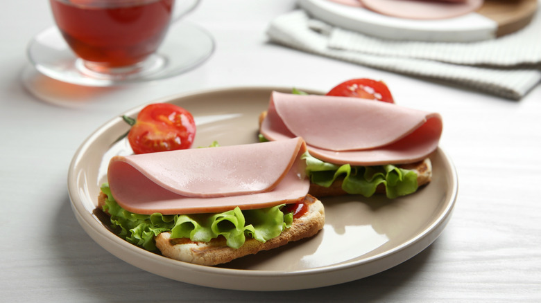slice of bread topped with lettuce, tomato, and a few slices of bologna