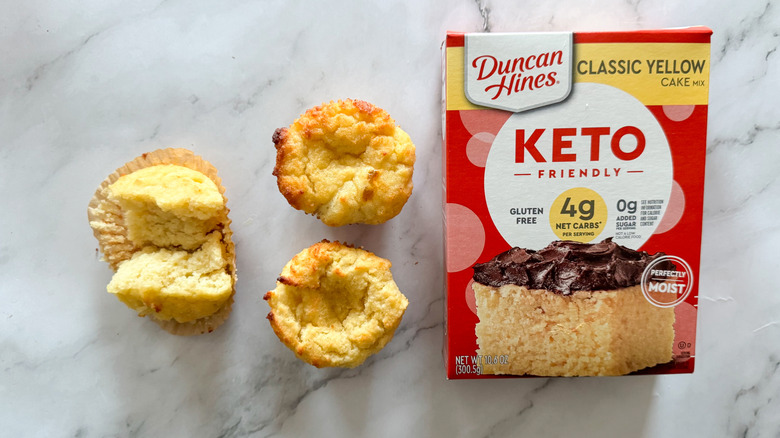 Duncan Hines keto cake mix on marble background with three cupcakes