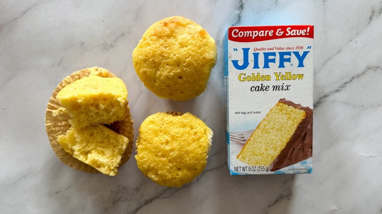 Jiffy yellow cake mix and cupcakes on marble surface