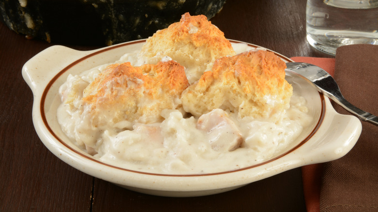 A serving of chicken pot pie casserole with a biscuit topping in a white ceramic bowl