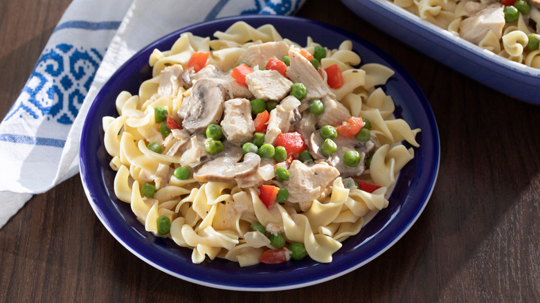 A blue bowl containing chicken a la king next to a blue and white napkin