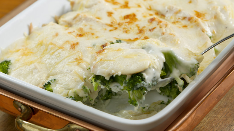 A chicken divan casserole in a ceramic dish placed in a copper casserole warmer