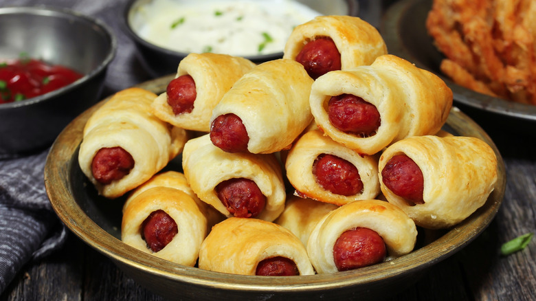 Pillsbury crescent dogs on a plate next to dipping sauces