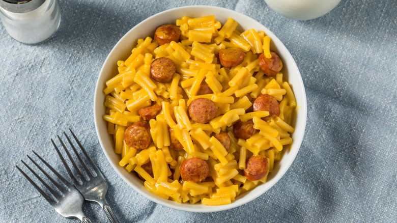 A bowl of mac and cheese topped with round pieces of hot dogs