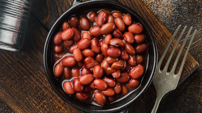 Top-down view of beans in a bowl with a can and fork