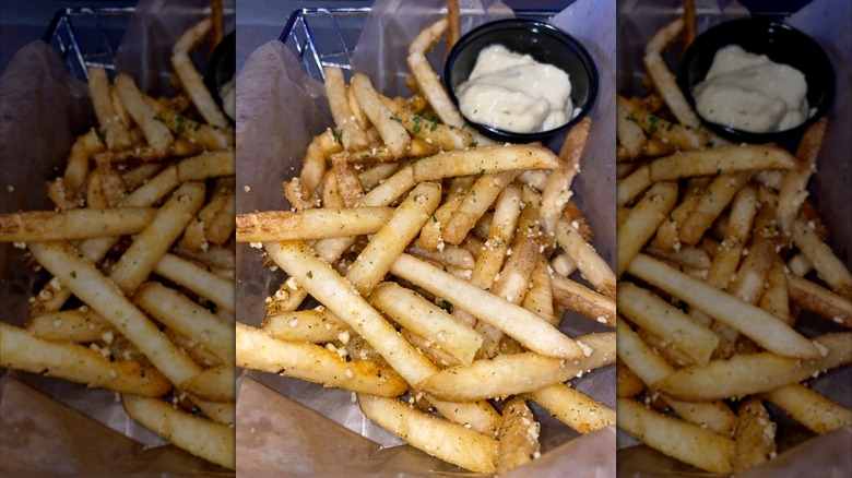 A basket of Fries GBT from Dave and Buster's on top of paper with a side of sauce, with mirror border