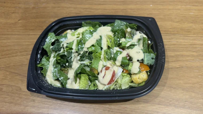 The Yard House's Kale & Romaine Caesar salad in a black to-go container