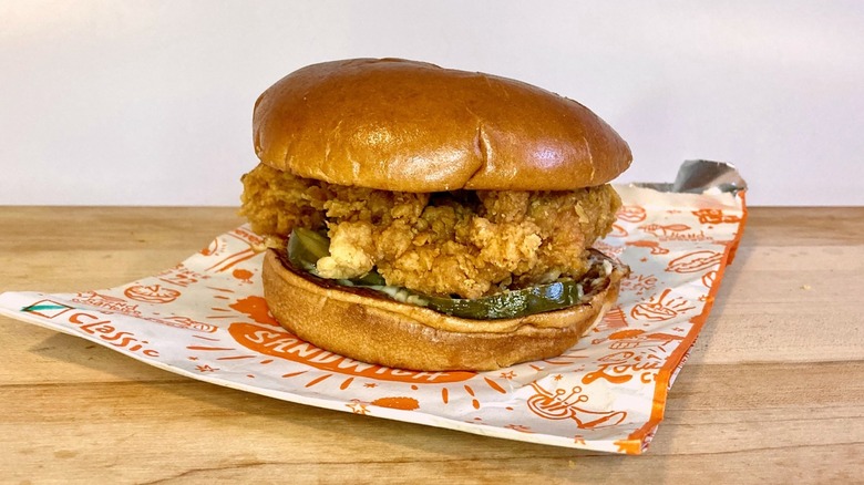Popeyes classic chicken sandwich on a wood table