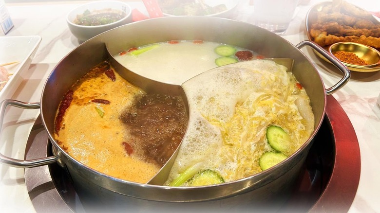 Three-compartment hot pot with broths and floating veggies at Nice to Meet You