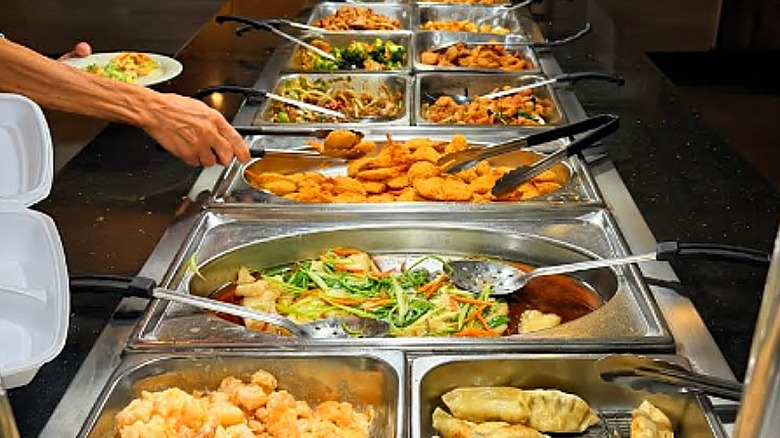 Customer helping themselves to Chinese food at Ultimate Buffet