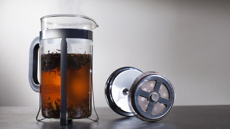 Coffee brewing inside a French press with the plunger sitting out