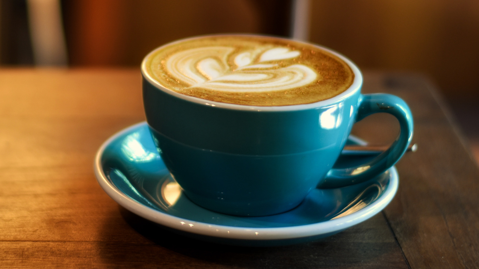 Latte art coffee on wooden table, cozy image for marketing