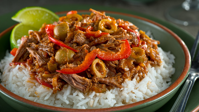ropa vieja served on a bed of rice, with a lime garnish