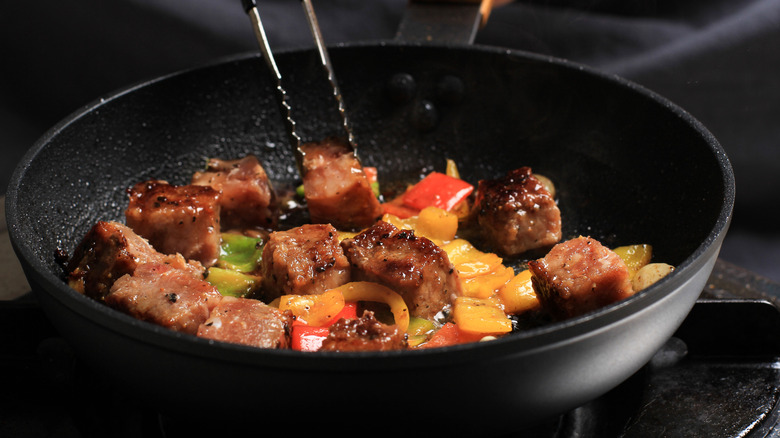 steak tips in a black skillet with colorful sweet peppers