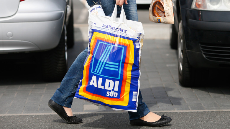 Someone on the street carrying a blue, yellow, orange, and white Aldi shopping bag