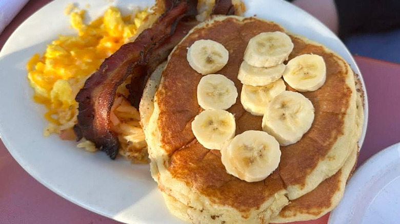 Pancakes toped with banana slices, scrambled eggs, and bacon at Ruth's Diner