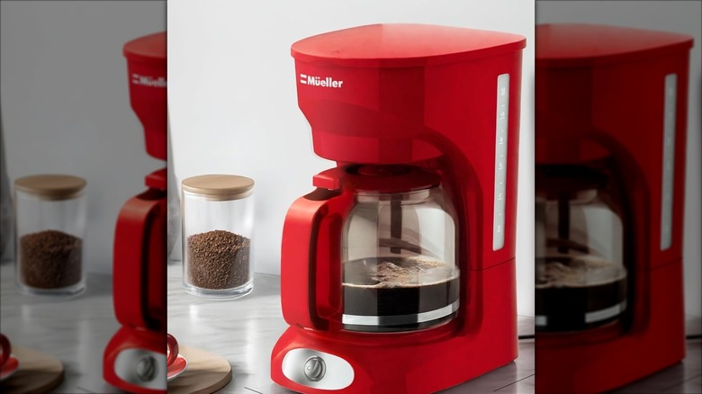 Red Mueller 12-cup drip coffee maker with jar of coffee grounds