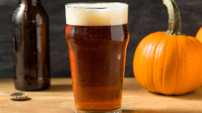 Beer in pint glass, pumpkin and beer bottle in background