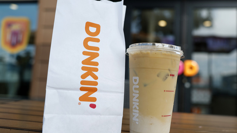 Dunkin' bag and drink on table outside