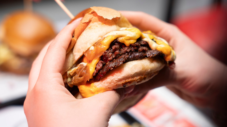 person holding a double cheeseburger