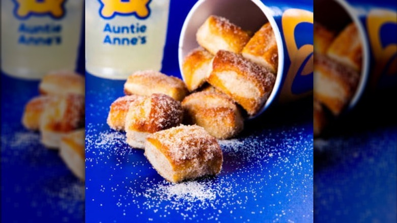 A tipped-over cup of Cinnamon Sugar Pretzel Bites with a cup of Auntie Anne's lemonade in the background